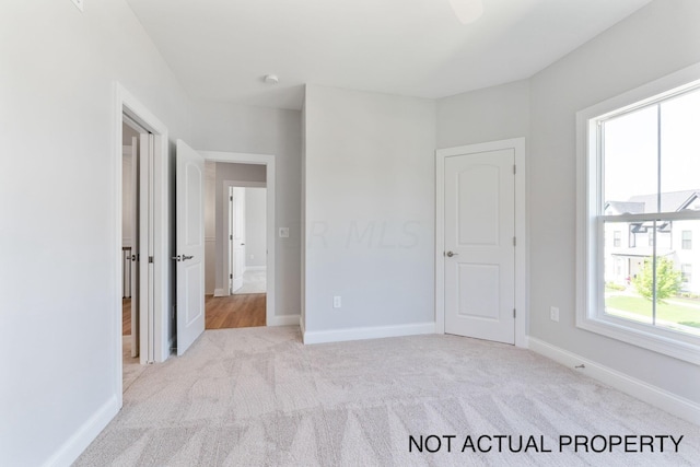 unfurnished bedroom featuring light colored carpet and multiple windows