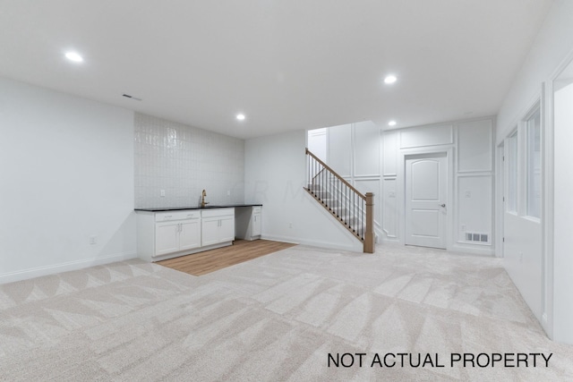 basement featuring light colored carpet and sink