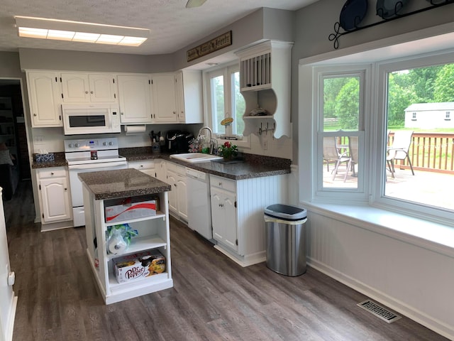 kitchen featuring white appliances, a center island, white cabinetry, and plenty of natural light