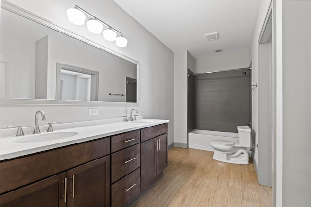 full bathroom featuring vanity, toilet, wood-type flooring, and tiled shower / bath combo