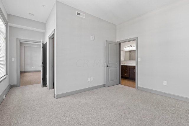 unfurnished bedroom featuring light colored carpet and multiple windows