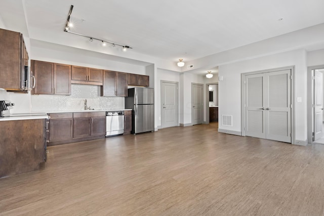 kitchen featuring tasteful backsplash, dark brown cabinets, stainless steel appliances, sink, and light hardwood / wood-style floors