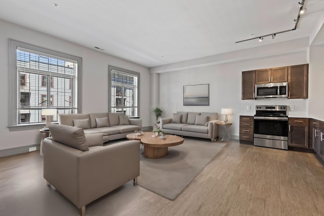 living room with light wood-type flooring and rail lighting