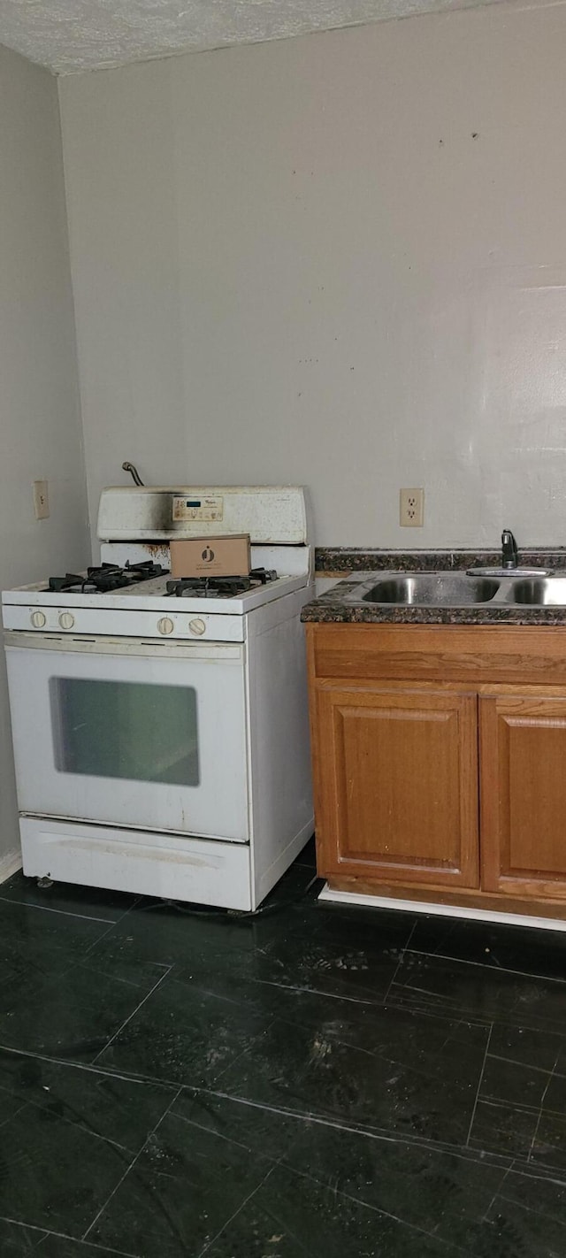 kitchen featuring sink, white gas stove, and a textured ceiling