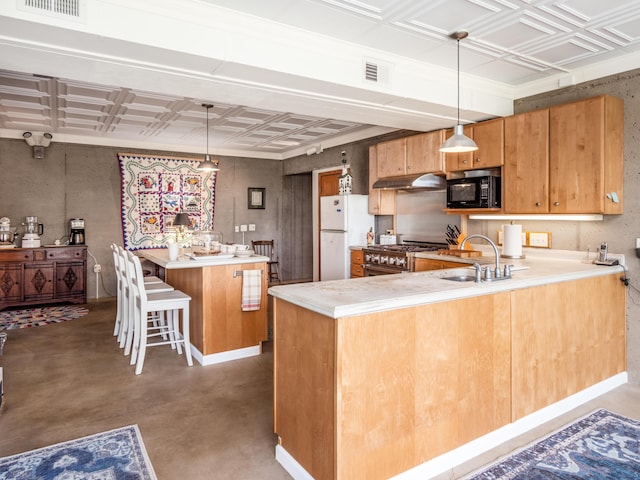 kitchen featuring high end range, hanging light fixtures, white fridge, kitchen peninsula, and a breakfast bar area