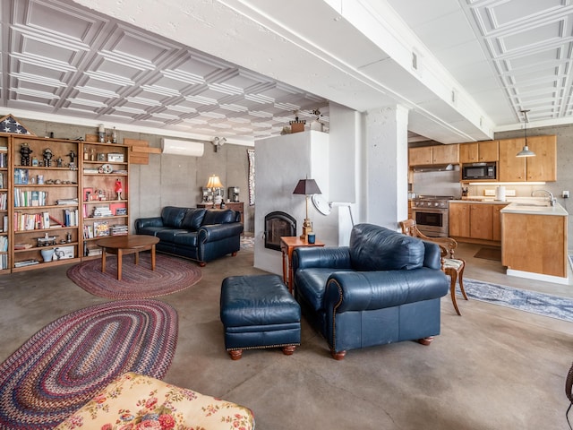 living room with concrete flooring, a wall unit AC, a fireplace, and sink