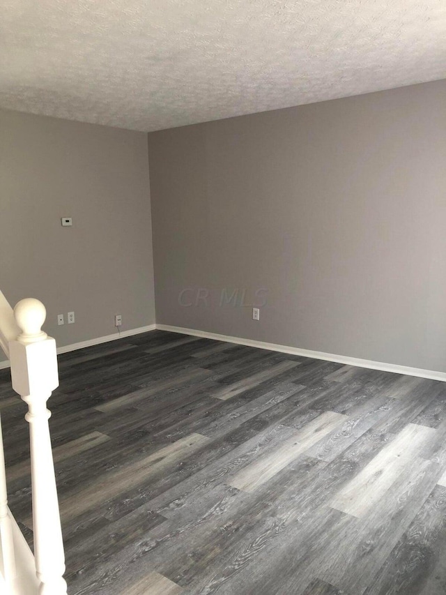 empty room with dark hardwood / wood-style floors and a textured ceiling