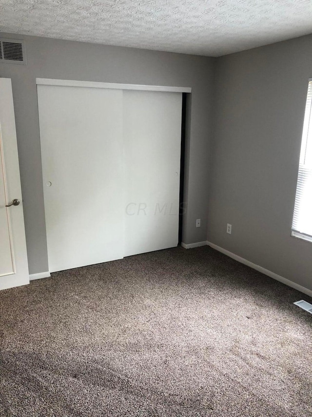 unfurnished room featuring carpet floors and a textured ceiling