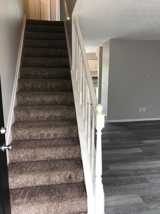 stairway with hardwood / wood-style floors and a textured ceiling