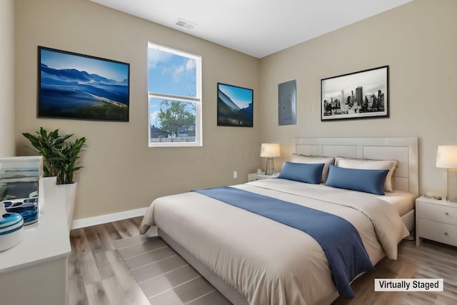 bedroom with electric panel and light hardwood / wood-style flooring