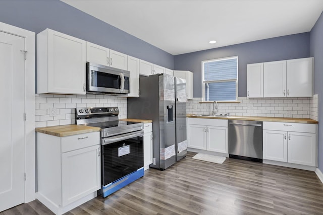 kitchen with wooden counters, stainless steel appliances, sink, hardwood / wood-style floors, and white cabinetry