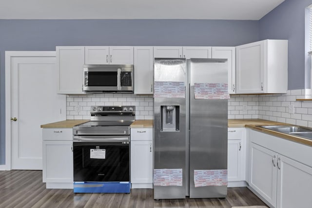 kitchen with white cabinets, stainless steel appliances, tasteful backsplash, and dark hardwood / wood-style floors