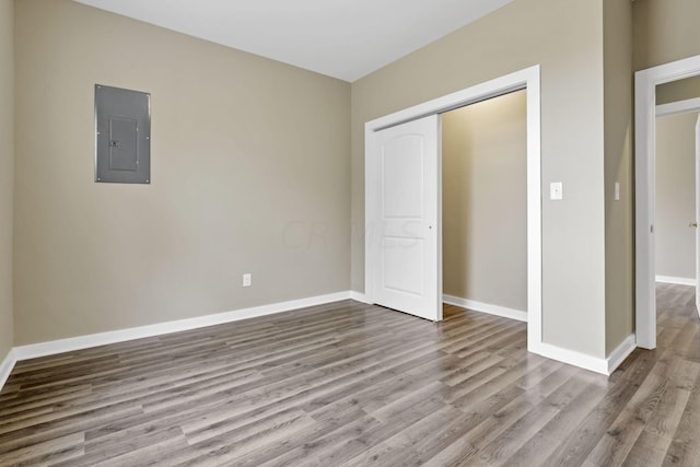 unfurnished bedroom with electric panel, a closet, and light hardwood / wood-style floors