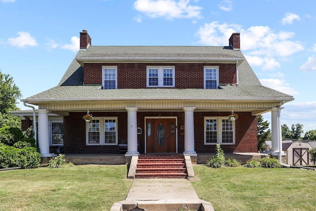 view of front of house with a front yard, a porch, and a storage unit