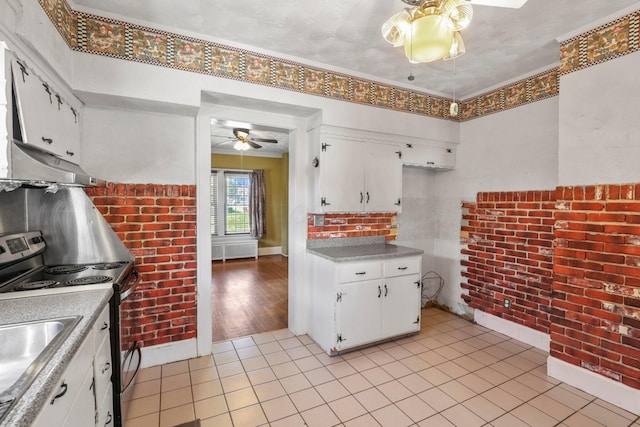 kitchen with stainless steel electric stove, white cabinets, ornamental molding, and light hardwood / wood-style flooring