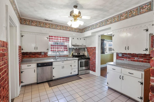 kitchen featuring ceiling fan, sink, stainless steel appliances, brick wall, and white cabinets