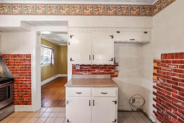 kitchen featuring light hardwood / wood-style flooring, white cabinetry, stainless steel range with electric stovetop, and ornamental molding