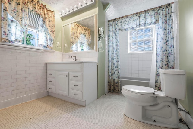 full bathroom with a textured ceiling, toilet, shower / tub combo with curtain, vanity, and tile walls