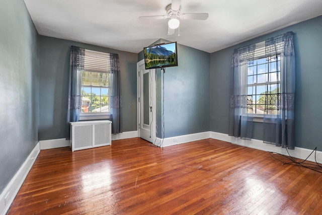 unfurnished room with ceiling fan, wood-type flooring, and radiator heating unit