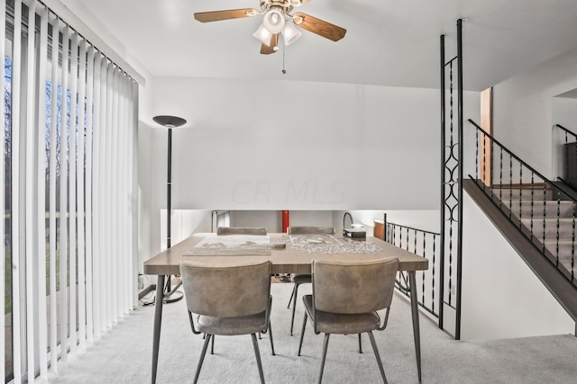 dining space featuring ceiling fan and light colored carpet