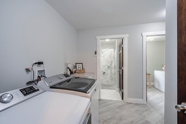 laundry room with light wood-type flooring and washer and clothes dryer