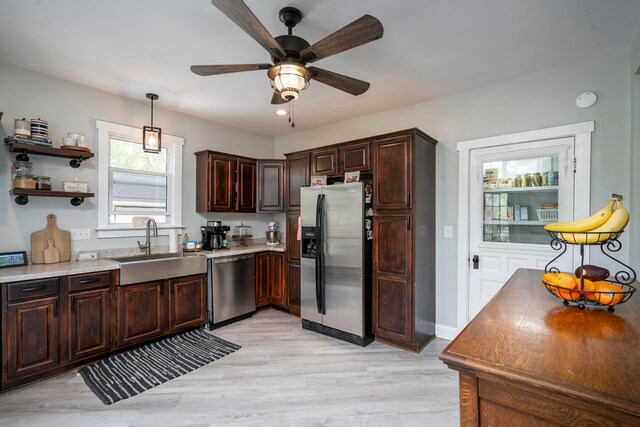 kitchen featuring appliances with stainless steel finishes, dark brown cabinets, sink, decorative light fixtures, and light hardwood / wood-style flooring