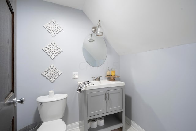 bathroom featuring vanity, toilet, and lofted ceiling