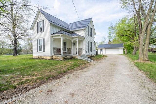 view of front of house featuring covered porch, a garage, an outdoor structure, and a front yard