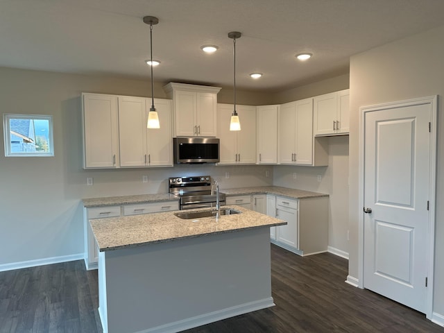 kitchen with pendant lighting, sink, light stone countertops, white cabinetry, and stainless steel appliances