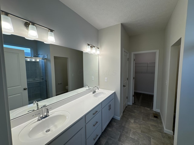 bathroom featuring a textured ceiling, vanity, toilet, and walk in shower