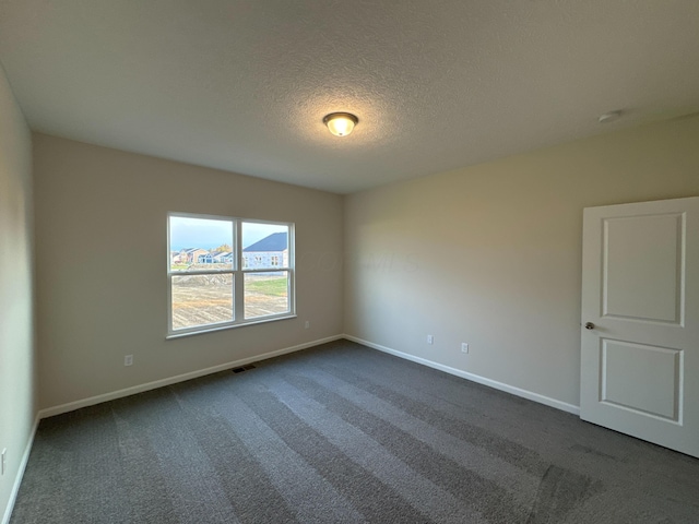 empty room with a textured ceiling and dark carpet