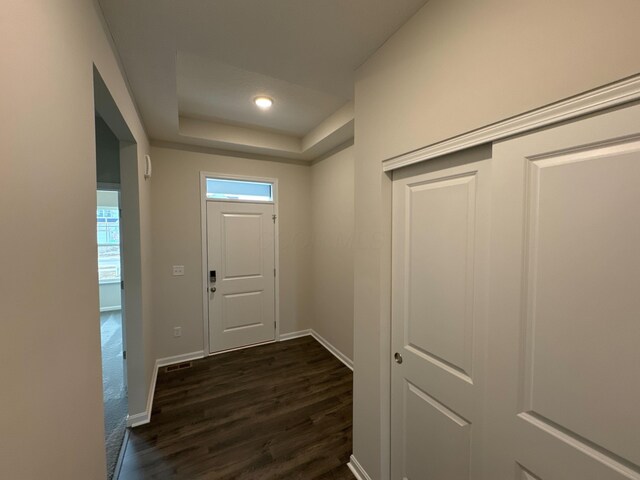 doorway to outside with a tray ceiling and dark hardwood / wood-style floors