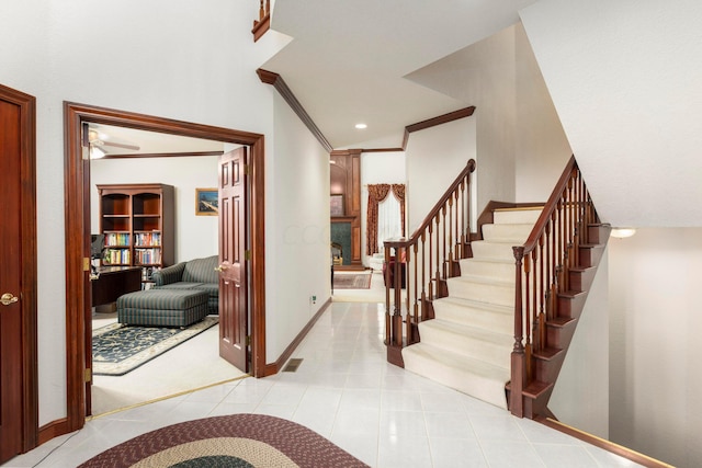 foyer with ceiling fan, light tile patterned floors, and crown molding