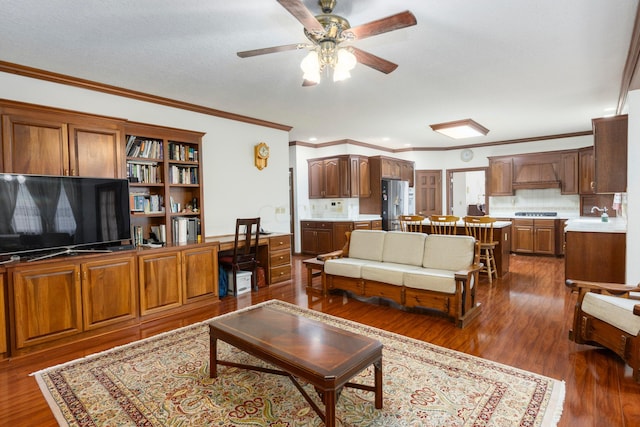 living room with a textured ceiling, dark hardwood / wood-style floors, ceiling fan, and ornamental molding