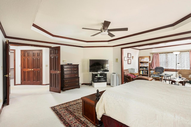 carpeted bedroom with a tray ceiling, ceiling fan, and ornamental molding