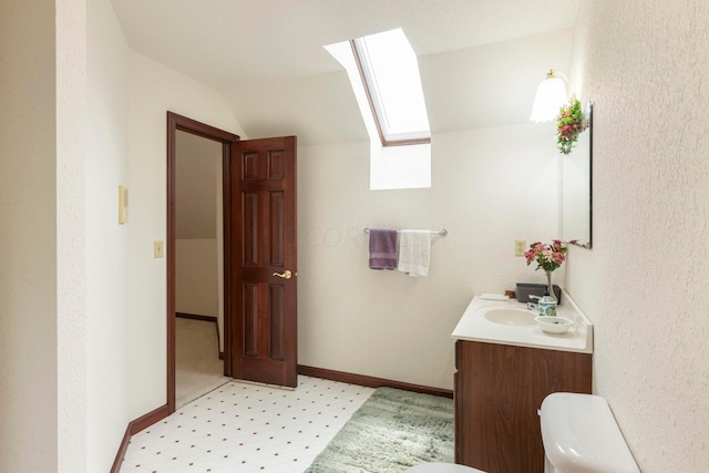 bathroom featuring vanity, toilet, and vaulted ceiling with skylight