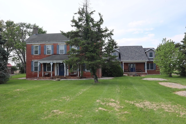 colonial house featuring covered porch and a front yard