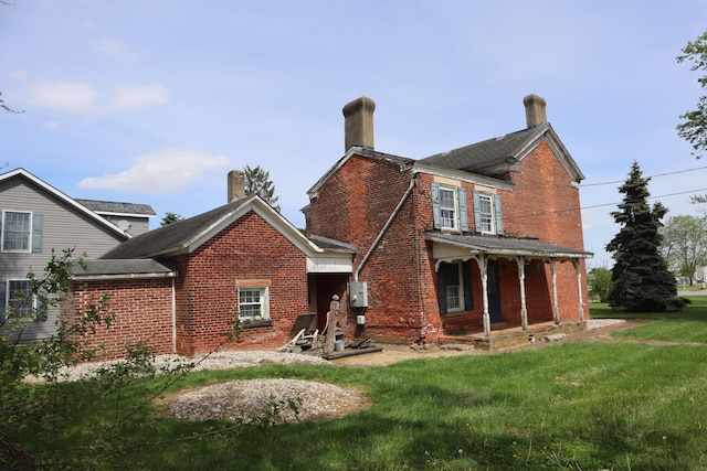 back of property with covered porch and a lawn