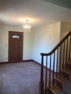 carpeted foyer featuring a chandelier