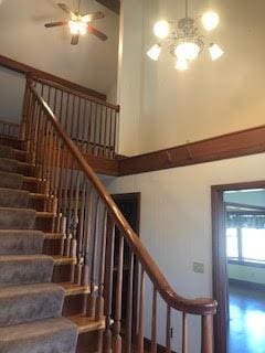 stairs with a high ceiling and ceiling fan with notable chandelier