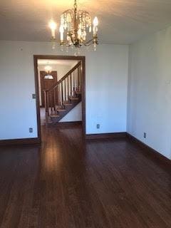 empty room featuring dark hardwood / wood-style floors and an inviting chandelier