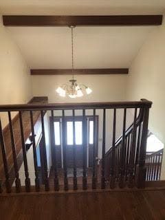 staircase featuring vaulted ceiling with beams and an inviting chandelier