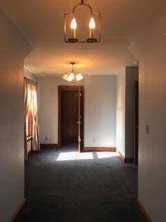 empty room featuring a chandelier and dark colored carpet