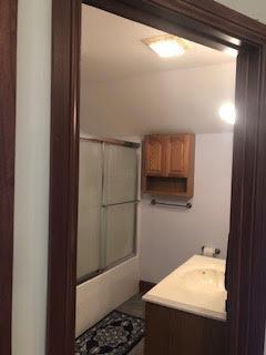 bathroom featuring vanity and bath / shower combo with glass door