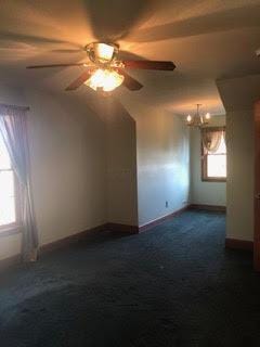 additional living space with ceiling fan and dark colored carpet