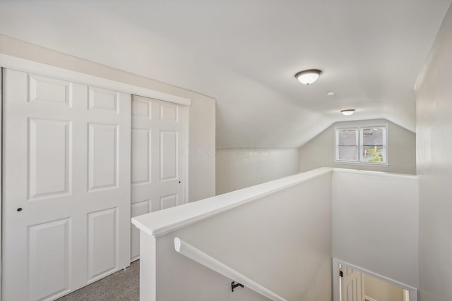 hall with dark colored carpet and lofted ceiling