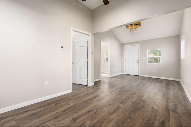 entrance foyer featuring ceiling fan with notable chandelier, dark wood-type flooring, and vaulted ceiling