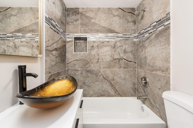 full bathroom featuring sink, tiled shower / bath, and toilet