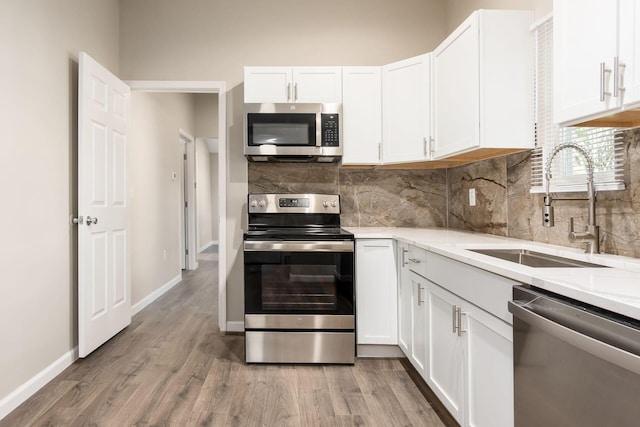 kitchen featuring white cabinets, appliances with stainless steel finishes, hardwood / wood-style flooring, and sink