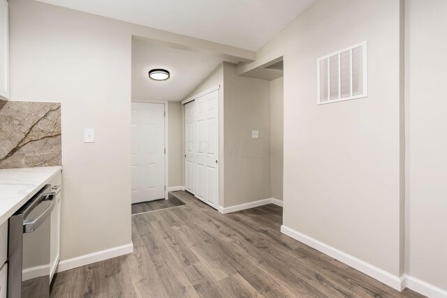 kitchen featuring light hardwood / wood-style flooring, stainless steel dishwasher, and vaulted ceiling